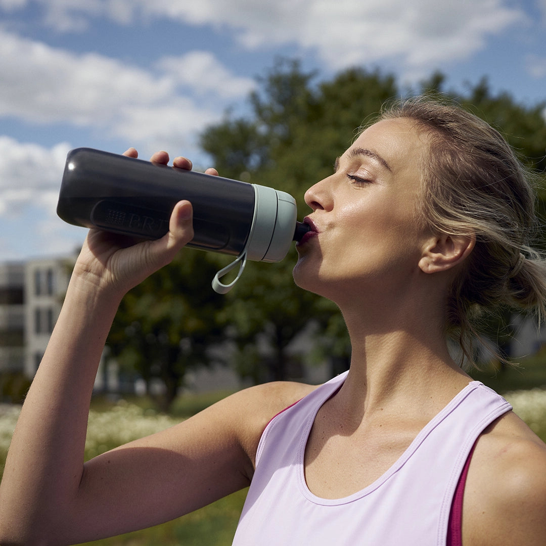 Woman drinking water from BRITA water filter bottle Model Active in green